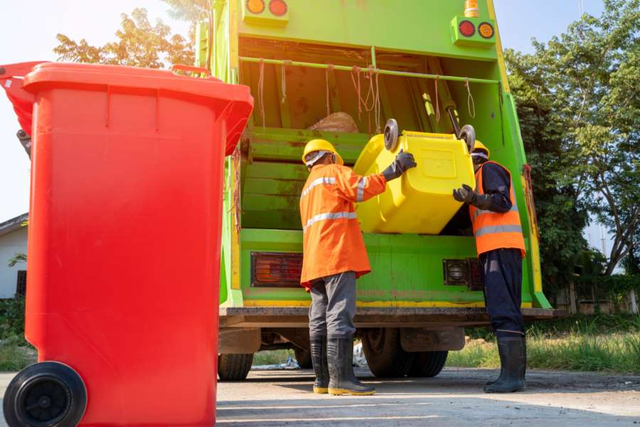 Cluttered driveway and professional crew hauling trash into a garbage truck, showcasing Junk removal services kent wa for residential cleanouts.
